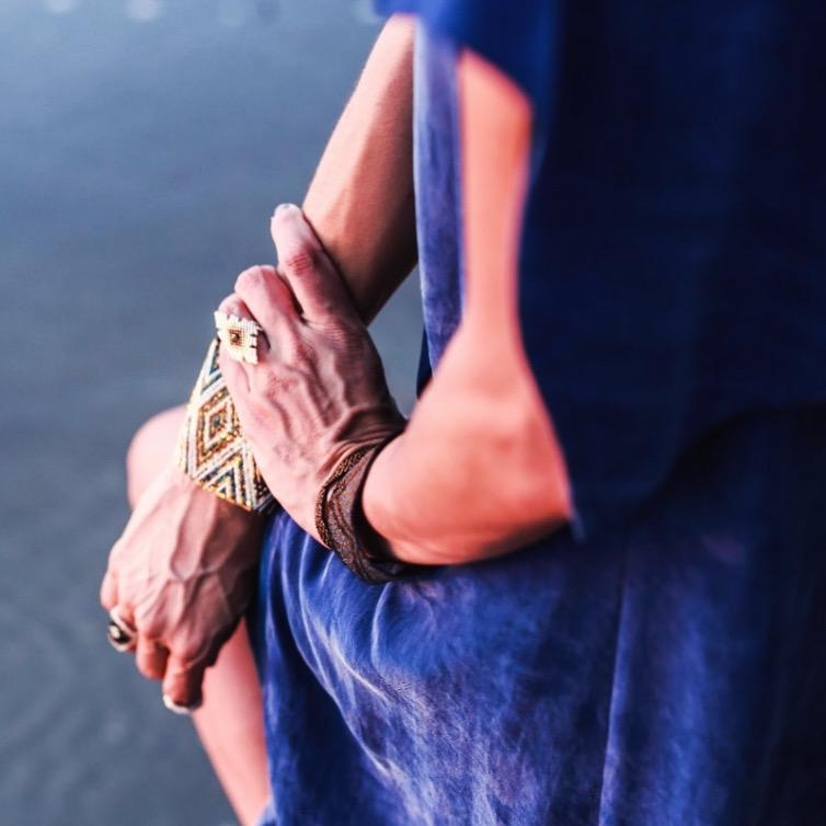 Détail de mains portant des bracelets et des bagues artisanales aux motifs géométriques.